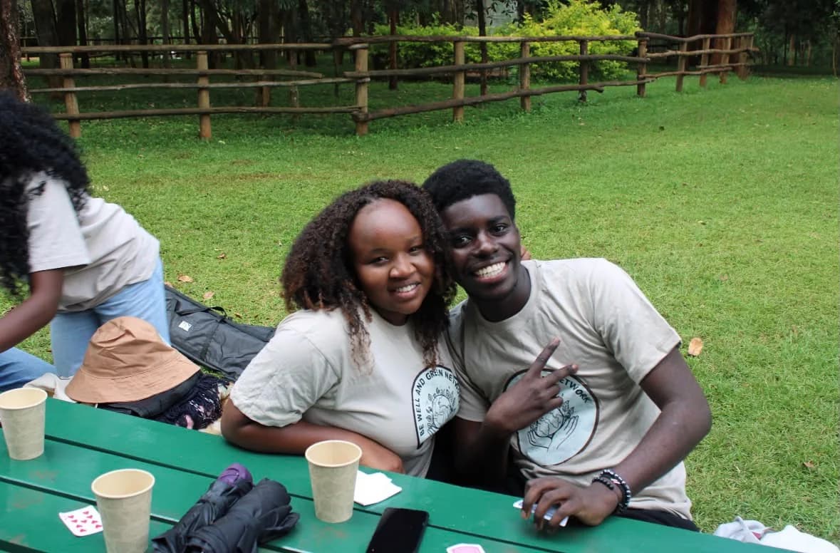Two BWGN volunteers in branded T-shirts sitting together at a picnic table in a park